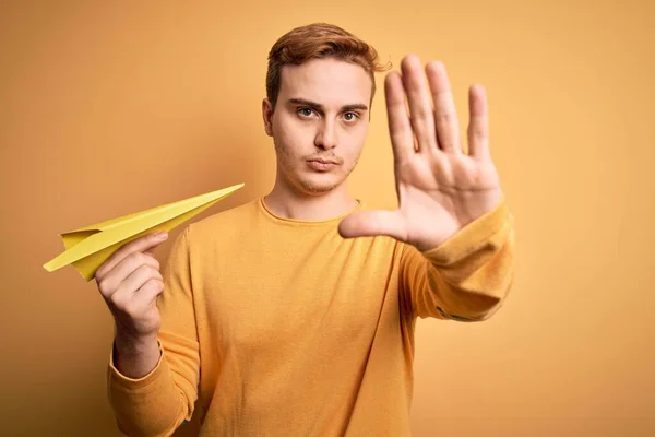 Junger Hübscher Rothaariger Mann Mit Papierflugzeug Vor Isoliertem Gelben Hintergrund — Stockfoto