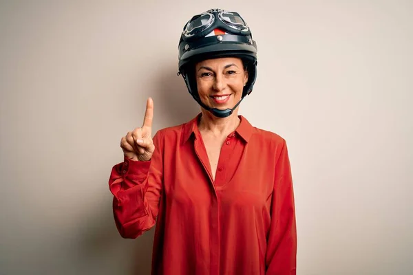 中年オートバイの女性身に着けていますオートバイヘルメット上の隔離された白い背景表示と指差しますとともに指第1自信と幸せ — ストック写真