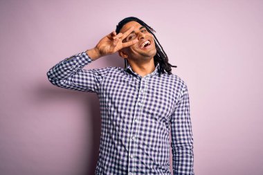 Rastgele gömlek giyen, yüzünde barış sembolü olan, gülümseyen, zafere gülümseyen Afro-Amerikan genç adam.