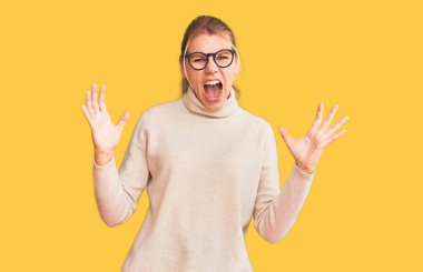 Balıkçı yaka kazak giyen, gözlüklü, deli gibi bağıran, sinirli ifadeli ve kollarını kaldırmış genç, güzel sarışın bir kadın. hüsran kavramı. 