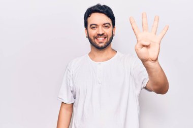 İspanyol asıllı genç adam, gündelik giysiler giyip dört numarayı gösterip işaret ederken kendinden emin ve mutlu bir şekilde gülümsüyor.. 