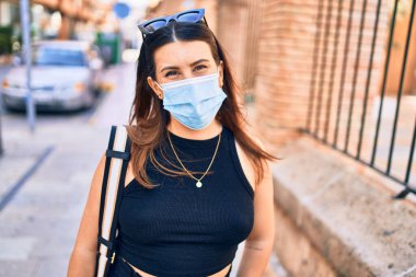 Tıbbi maske takan güzel esmer bir kadın. Şehir caddesinde yürürken
