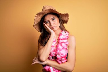 Tatilde mavi gözlü, bikini giyen ve Hawaii zambağı giyen genç ve güzel bir kadın kollarını kavuşturarak depresyondan sıkılmış ve yorgun göründüğünü düşünüyor..