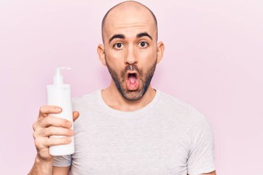 Genç, yakışıklı, kel bir adam elinde krem losyon şişesi tutuyor. Korkmuş ve şaşkına dönmüş bir halde ağzı açık şaşkınlık içinde, inançsız bir yüz. 