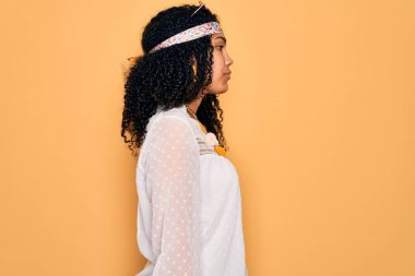 Afro-Amerikan kıvırcık saçlı, güneş gözlüğü takan, klasik aksesuarlar takan, rahat bir görünüm takınan, kendine güvenen, kendine güvenen bir gülümseme takınan genç bir kadın..