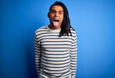 Rasta desenli çizgili süveter giyen, neşeli bir ifadeyle dilini dışarı çıkaran Afro-Amerikan genç adam. Duygu kavramı.