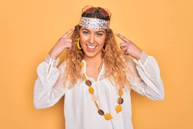 Genç, sarışın, mavi gözlü, güneş gözlüklü ve aksesuarlı, iki eliyle başını gösteren güzel bir hippi kadın. Harika bir fikir ya da düşünce, iyi bir hafıza.