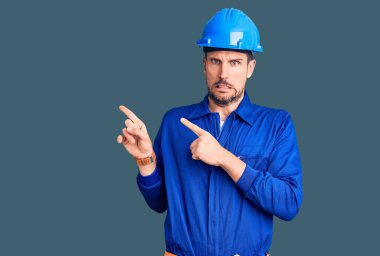 Genç, yakışıklı, işçi üniforması giyen ve kasketli bir adam bir soru hakkında endişeli ve gergin bir şekilde düşünüyor. 