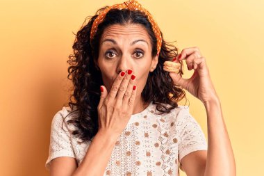 Orta yaşlı güzel bir kadın, elinde makaronla ağzını kapatıyor, şok geçiriyor ve hata yapmaktan korkuyor. şaşırmış ifade 