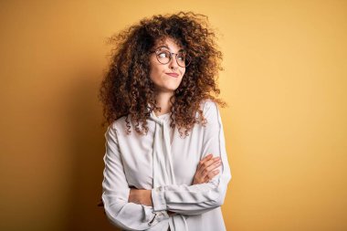 Genç, güzel esmer, kıvırcık saçlı, piercing takan, gömlek ve gözlük takan, gülümseyen ve düşüncelere dalan bir kadın..