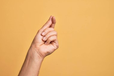 İzole edilmiş sarı arka planda parmaklarını gösteren beyaz bir adamın eli. Parmak, iş ve reklamla boş bir alan tutuyor.