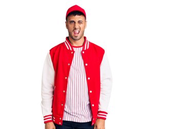 Beyzbol forması giyen genç İspanyol adam kameraya seksi bir ifadeyle bakıyor, neşeli ve mutlu bir yüz.. 