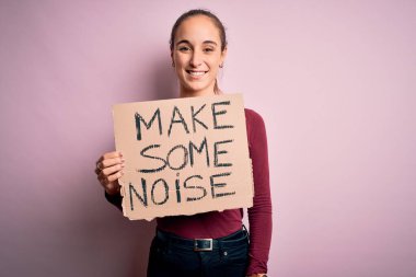 Elinde bayrak tutan güzel aktivist kadın pembe arka planda gülen bir yüzle, kendine güvenen bir gülümsemeyle dişlerini gösteren gürültülü bir mesaj veriyor.