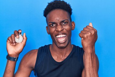 Kronometre tutan genç Afrikalı Amerikalı adam gururla bağırıyor zaferi ve başarıyı kutluyor. 