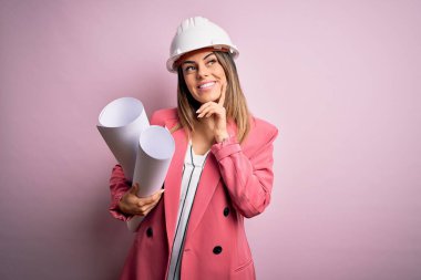 Genç, güzel, esmer, kasklı, kasklı bir kadın. Elinde planlar, ciddi bir yüz var. Soru sormayı düşünüyor, kafası karışık bir fikir.