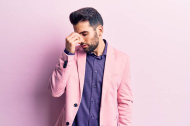 Sakallı, zarif ceketli, burnu ve gözleri ovuşturmaktan yorgun, yorgun ve baş ağrısı çeken genç yakışıklı bir adam. Stres ve hüsran kavramı. 