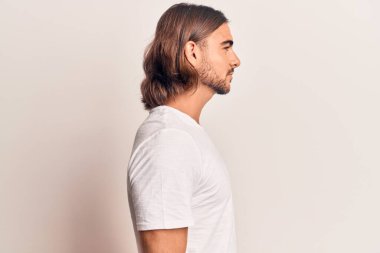 Sıradan kıyafetler giyen genç yakışıklı bir adam, rahat bir görünüm takınıyor kendine güvenen bir gülümsemeyle doğal bir yüz ifadesi takınıyor.. 