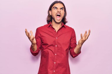 İş kıyafetleri giyen genç yakışıklı çılgın ve kızgın bir adam agresif bir ifadeyle bağırıyor ve kollarını kaldırıyor. hüsran kavramı. 