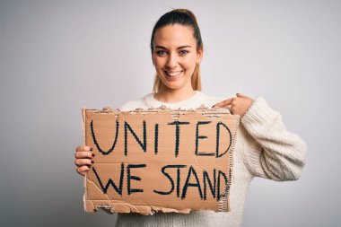 Mavi gözlü, genç, sarışın, birleşik bir bayrak tutan, kendini gösteren sürpriz yüzlü bir kadın.
