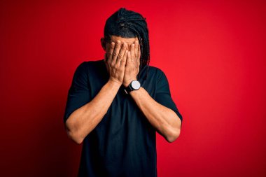 Genç, yakışıklı, Afro-Amerikan Afrikalı, rastalı tişörtlü, üzgün suratını elleriyle kapatan ve ağlayan bir adam. Depresyon kavramı.