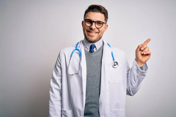 의사가 코트와 청진기를 착용하고 위에서 미소를 카메라를 쳐다보면서 손가락으로 가리키고 — 스톡 사진