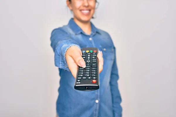 Woman changing television channel holding tv remote control. Standing over isolated white background