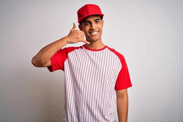 縞模様の野球Tシャツを着た若いハンサムなアフリカ系アメリカ人のスポーツマンとキャップは 電話で話すような手と指で電話のジェスチャーをして笑顔 概念の伝達 — ストック写真