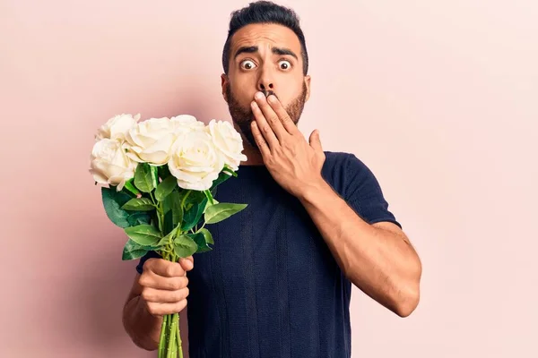 Jovem Hispânico Segurando Flores Cobrindo Boca Com Mão Chocado Com — Fotografia de Stock