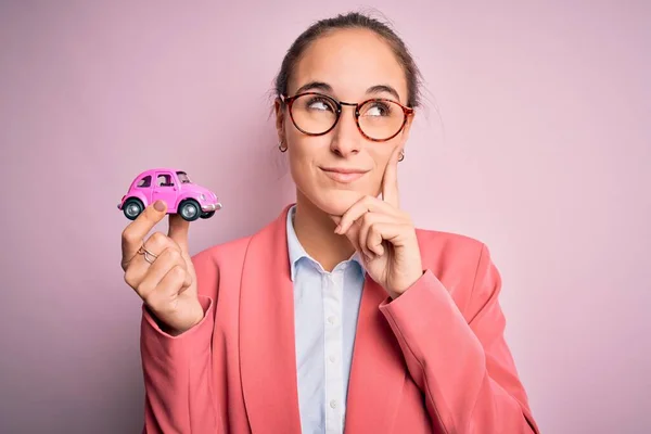 Νεαρή Όμορφη Επιχειρηματίας Φορώντας Γυαλιά Κρατώντας Ροζ Αυτοκίνητο Παιχνίδι Πάνω — Φωτογραφία Αρχείου