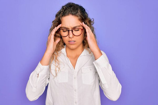 Young beautiful woman with blue eyes wearing casual shirt and glasses over purple background with hand on head for pain in head because stress. Suffering migraine.
