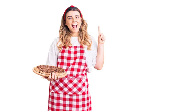 Mujer Joven Caucásica Con Delantal Sosteniendo Pizza Sorprendida Con Una — Foto de Stock