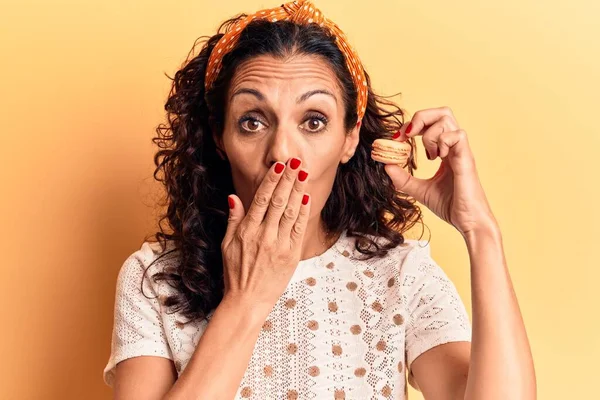 Orta yaşlı güzel bir kadın, elinde makaronla ağzını kapatıyor, şok geçiriyor ve hata yapmaktan korkuyor. şaşırmış ifade 