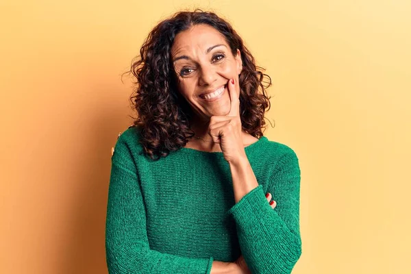 Orta yaşlı, süveter giyen güzel bir kadın kameraya kolları çapraz ve çenesi açık gülümsüyor. Olumlu düşünmek. 