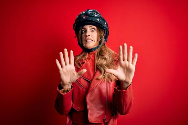 若い美しいブルネットのオートバイの女性はショックで叫んで 赤い背景の上に元ヘルメットを身に着けている恐怖表現で恐れて手でジェスチャーを停止します パニック概念 — ストック写真