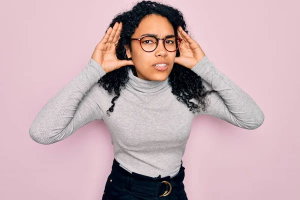 Młoda Afroamerykanka Swetrze Okularach Różowym Tle Próbująca Usłyszeć Obie Dłonie — Zdjęcie stockowe