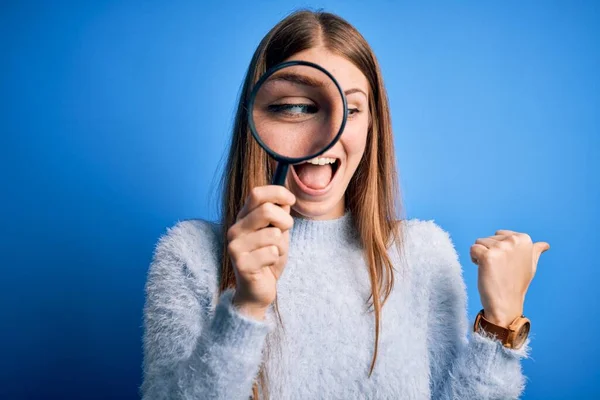 Jovem Bela Mulher Detetive Ruiva Usando Lupa Sobre Fundo Azul — Fotografia de Stock