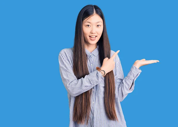 Młoda Piękna Chinka Ubrana Luźną Koszulę Zdumiona Uśmiechnięta Aparatu Prezentując — Zdjęcie stockowe