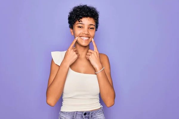 年轻美丽的非洲裔美国女人 身穿浅紫色背景的休闲T恤 张开嘴 手指指尖 笑容可亲 — 图库照片