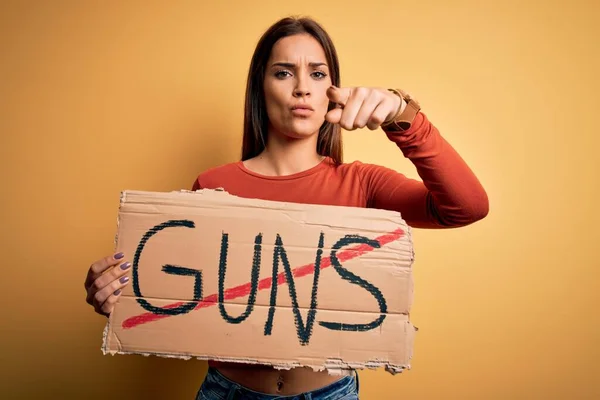 若い美しい活動家の女性は カメラとあなたに指で指すストップ銃のメッセージと平和保持バナーを求めて 手のサイン 正とフロントから自信を持ってジェスチャー — ストック写真