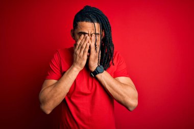 Kırmızı günlük tişörtler giyen, yorgun, uykulu ve yorgun ifadeler takınan, yorgun ve yorgun bakışları olan Afro-Amerikan genç yakışıklı bir adam. Görüş sorunu