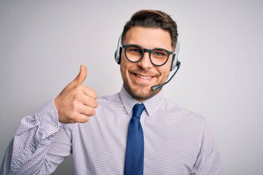 Genç çağrı merkezi operatörü mavi gözlü, gözlüklü ve kulaklık takan el hareketleriyle mutlu mesut hareket eden bir iş adamı. Kameraya bakıp başarıyı gösteren ifade onaylanıyor.