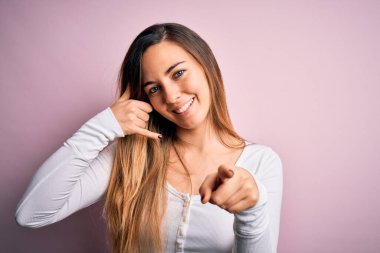 Genç, güzel, sarışın, mavi gözlü, pembe arka planda beyaz tişört giyen, gülümseyen, telefonda konuşan ve seni işaret eden bir kadın. Ara beni..