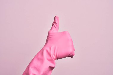 İzole edilmiş pembe arka planda temiz eldiveni olan beyaz bir gencin eli başarılı bir onay jesti yapıyor. Başparmak işareti, onaylama ve olumlu bir sembol.