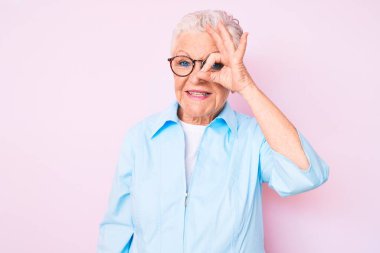 Mavi gözlü, gri saçlı, gülümseyen, mutlu bir şekilde gülümseyen yaşlı ve güzel bir kadın. 