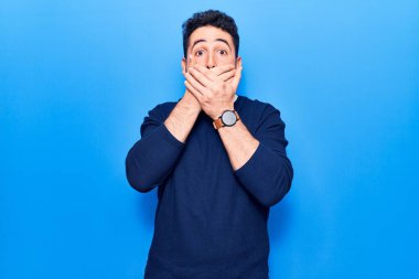 Gündelik kıyafetler giyen genç İspanyol adam yanlışlıkla elleri ile ağzını kapatırken şok oldu. gizli kavram. 