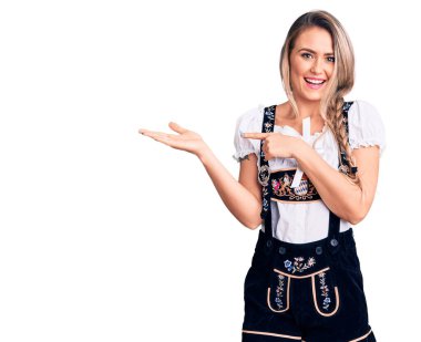 Oktoberfest elbisesi giyen genç ve güzel sarışın kadın kameraya hayret ediyor ve gülümsüyor.. 