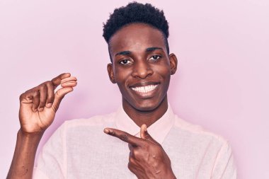 Makarna tutan genç Afrikalı Amerikalı adam gülümsüyor mutlu bir şekilde el ve parmağıyla işaret ediyor. 