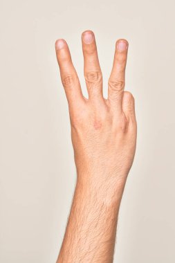 Beyaz arka planda parmaklarını gösteren beyaz tenli bir gencin eli üç parmağı gösteriyor.