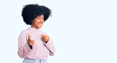 Sıradan kıyafetler giymiş genç Afro-Amerikalı kız mutlu ve komik yüzüyle kamerayı işaret ediyor. iyi enerji ve titreşimler. 