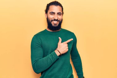 Genç Arap adam gündelik giysiler giyiyor. Gülümsüyor, elleri ve parmakları yana doğru uzanıyor. 